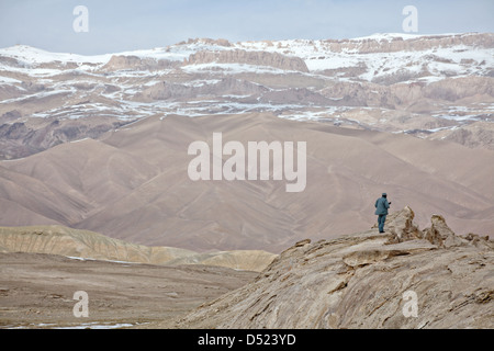 Una polizia nazionale afgana officer fornisce la sicurezza sulla cima di una collina che domina una valle Marzo 11, 2013 in provincia di Bamiyan, Afghanistan. Foto Stock