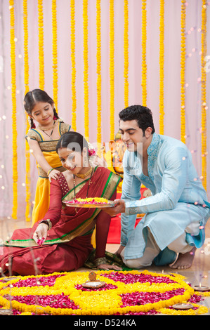 Famiglia Maharashtrian rendendo flower rangoli durante ganesh chaturthi festival Foto Stock