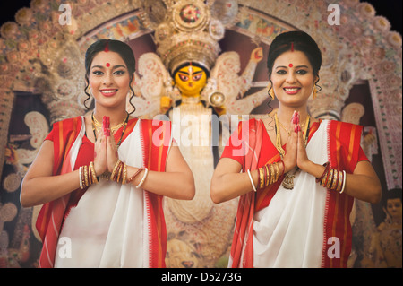 Le donne bengalesi in piedi in una posizione di preghiera a Durga Puja Foto Stock