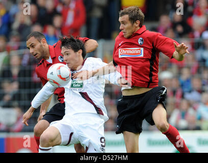 Freiburg's Oemer Toprak e Julian Schister (R) vie per la palla con il Kaiserslautern Srdjan Lakic (C) durante il match della Bundesliga SC Freiburg vs FC Kaiserslautern in Badenova stadium a Friburgo in Germania il 23 ottobre 2010. Foto: Patrick Seeger (ATTENZIONE: embargo condizioni! Il DFL permette l'ulteriore utilizzazione delle immagini nella IPTV, servizi di telefonia mobile e altre nuove tec Foto Stock