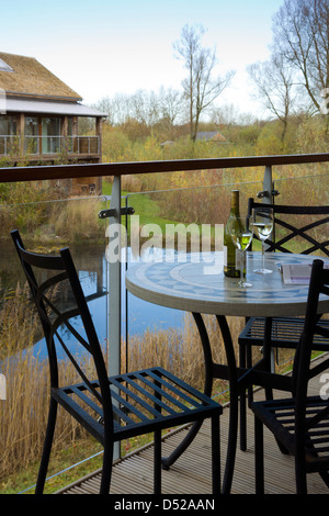 Un piccolo tavolo con sedie in una casa vacanze veranda con vista su un piccolo lago, Gloucestershire, England, Regno Unito Foto Stock