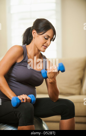 Incinta donna ispanica sollevamento pesi Foto Stock