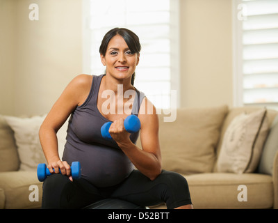 Incinta donna ispanica sollevamento pesi Foto Stock