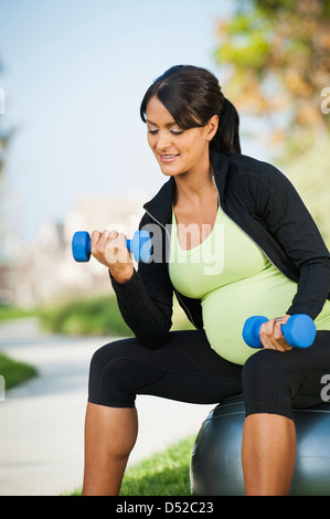 Incinta donna ispanica sollevamento pesi all'aperto Foto Stock