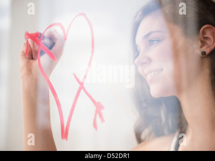 Ragazza ispanica disegno cuore con la freccia sulla finestra Foto Stock