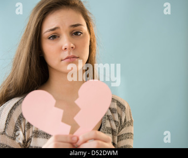 Ragazza ispanica holding cuore spezzato la forma Foto Stock