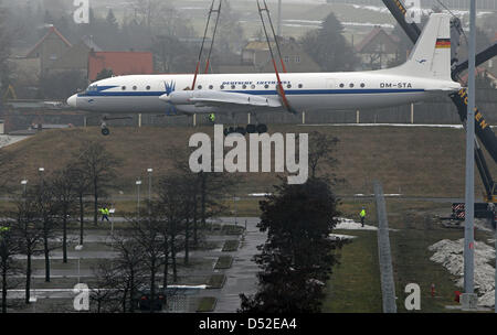 Una gru porta un Ilyushin IL 18 aereo oltre lo spazio di parcheggio dell'aeroporto di Leipzig/Halle in Schkeuditz, Germania, 24 febbraio 2010. Il velivolo con il dipinto originale di Lufthansa Ost è la prima esposizione del futuro aeroporto Eventpark e sarà aperta ai visitatori. L'aereo sovietico è stato in funzione dal 1960 al 1988 per Lufthansa Ost e Interflug. Foto: JAN WOITAS Foto Stock