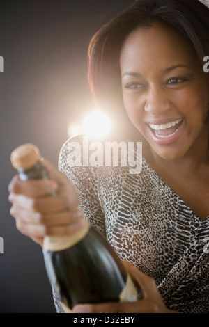 African American donna apertura della bottiglia di champagne Foto Stock