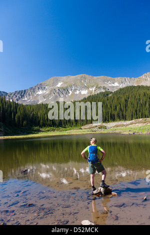 Escursionista caucasica permanente sulla roccia nel lago Foto Stock