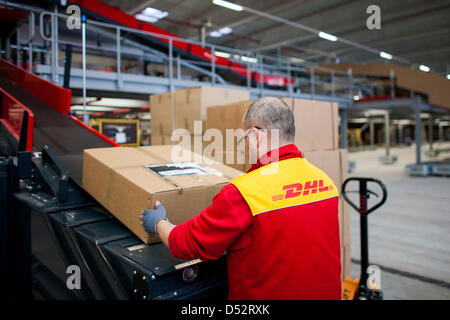 Un dipendente di Deutsche Post DHL mette un pacchetto sulla linea di montaggio in corrispondenza del primo meccanica del punto di consegna a Bochum, Germania, 20 marzo 2013. È il secondo sistema nazionale che legge i pacchetti automaticamente e li distribuisce al trasportatore. Foto: Rolf Vennenbernd Foto Stock
