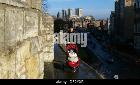 Una giovane madre con il suo passeggino in York mura con il Ministro al di là di Foto Stock