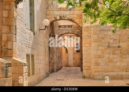 Narrown strada di ciottoli tra denocciolate tradizionali case del quartiere ebraico al centro storico della città di Gerusalemme. Foto Stock