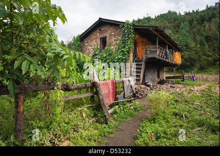 Tradizionale in pietra a secco wall house con sulla pannocchia di mais essiccamento sulla terrazza all'aperto, Sangti village, Dirang, Tawang. Foto Stock