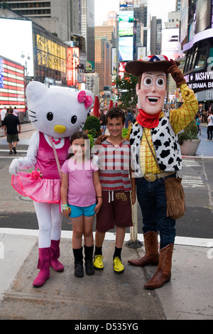 Hello Kitty e Toy Story Woody personaggio dei fumetti costumi in posa con i bambini in Times Square a New York Foto Stock