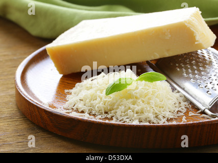 Formaggio parmigiano grattugiato e grattugia di metallo sul piatto di legno Foto Stock