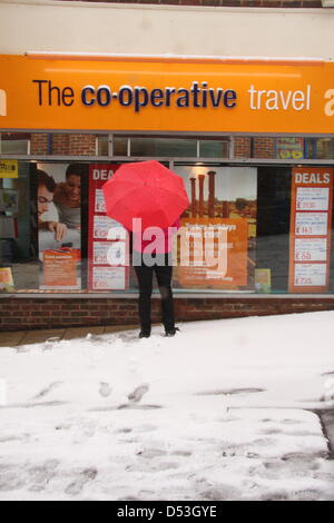 Shopper sogni di climi più soleggiato al travel agent finestra della molla durante la tempesta di neve, Regno Unito, Foto Stock