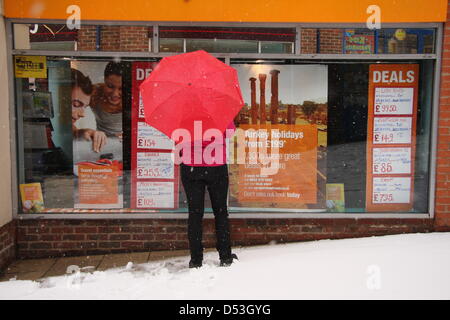 Shopper sogni di climi più soleggiato al travel agent finestra della molla durante la tempesta di neve, Regno Unito, Foto Stock