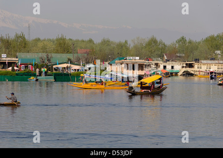 Shikaras e case galleggianti lungo con un giardino in dal lago a Srinagar. Una vista tipica della scena sul lago in qualsiasi giorno. Foto Stock