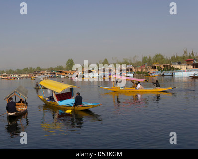 Numero multiplo di shikaras sull'acqua del dal Lago a Srinagar con lo sfondo delle case galleggianti e cielo blu Foto Stock