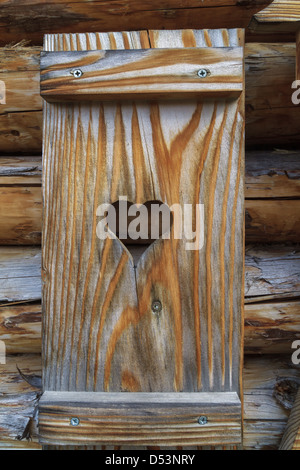 Otturatore della finestra con il cuore di una capanna di legno delle Alpi in Europa Foto Stock