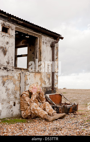 Soldato sofferenza con proprio Disturbo Post-traumatico da Stress sul campo di battaglia. Soldato indossa militare britannico uniforme del deserto. Foto Stock