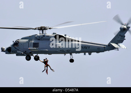 Un US Naval Air equipaggio è sollevato dall'acqua da un SH-60B Mare Hawk elicottero durante una ricerca ed esercitazione di soccorso 11 marzo 2013 nel Mare Arabico. Foto Stock