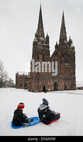 Lichfield Cathedral, Staffordshire, Regno Unito. Il 24 marzo 2013. Due giovani ragazzi godendo in slittino unseasonal neve nel chiudere davanti a Lichfield Cathedral Staffordshire su Palm domenica 24 marzo 2013 Foto Stock
