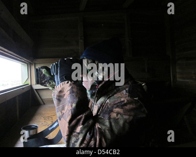 Coppia ragazzo in un freddo nascondi bird watching, indossare abbigliamento camouflage. Il 24 marzo 2013 Foto Stock