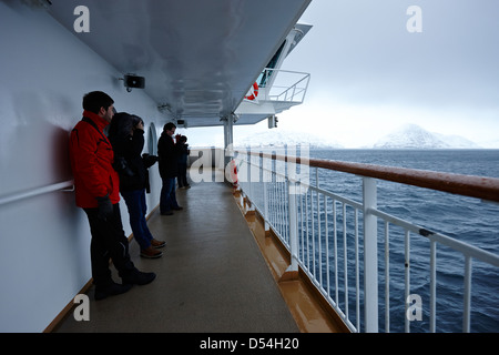 I passeggeri a bordo di hurtigruten nave passeggeri vela attraverso fiordi durante l'inverno la Norvegia europa Foto Stock