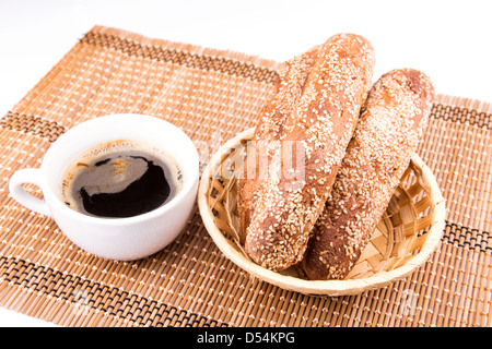 Pane appena sfornato rotoli con sesamo con tazza di caffè servito su un tovagliolo isolato su bianco Foto Stock