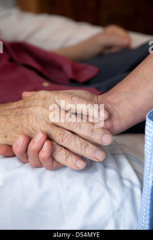 In Germania, la mano di un infermiere tiene la mano di un uomo morente Foto Stock