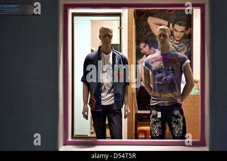 Le ore notturne accese shop window display dotato di manichini in abbigliamento Foto Stock