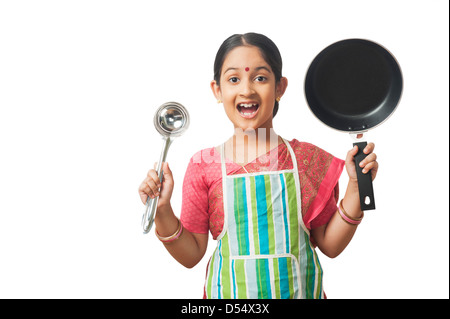 Ragazza imitando come donna holding padella con un cucchiaio Foto Stock