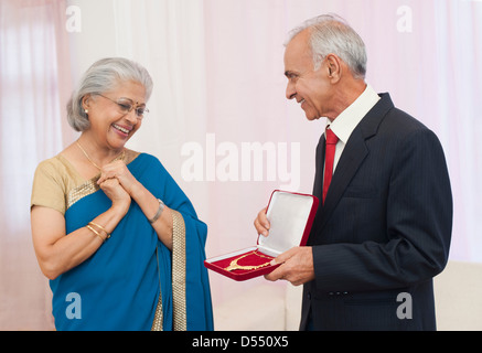 L uomo dando gioielli a sua moglie il loro anniversario Foto Stock