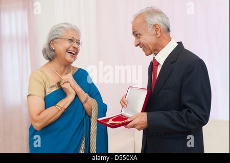 L uomo dando gioielli a sua moglie il loro anniversario Foto Stock