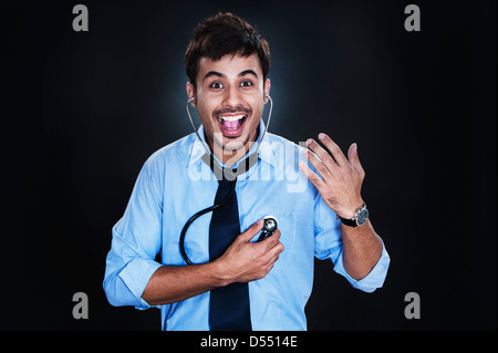 Close-up di un imprenditore ascoltare il suo battito cardiaco con uno stetoscopio e ridere Foto Stock