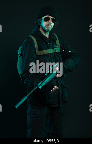 Sniper con la barba di nero che tiene la pistola. Studio shot. Foto Stock
