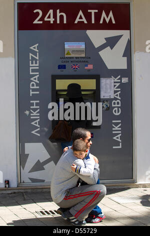 Nicosia, Cipro. 25 marzo, 2013. Padre cipriota tiene il suo giovane figlio al di fuori di una banca Laiki filiale per le strade di Nicosia, dopo che il Presidente Anastasiades concordato di bailout piani con funzionari UE. Foto Stock