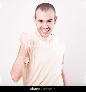 Ritratto di un entusiasta giovane celebra il successo con mano sollevata contro uno sfondo bianco Foto Stock