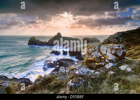 Picchi di luce del sole da dietro le nuvole di pioggia la creazione di raggi di sole su Kynance Cove, Cornwall, Inghilterra Foto Stock
