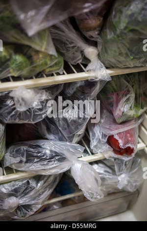 Un frigorifero con ripieno di verdure in plastica produzione di sacchetti è visto a New York Foto Stock