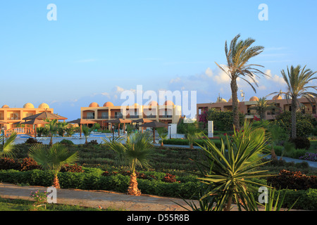 I caldi raggi del tramonto illuminano l'hotel con palme sul mare Foto Stock