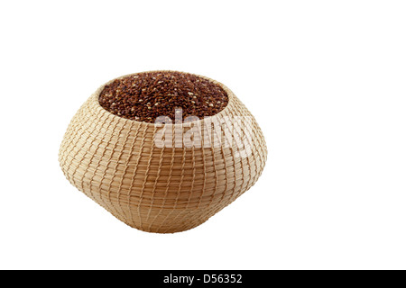 Quinoa rosso biologico (Chenopodium quinoa) in un cestino maya realizzato in Lubaantun, Belize, su sfondo bianco Foto Stock