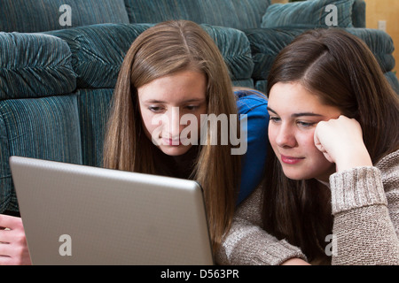 Due ragazze adolescenti sul soggiorno piano attentamente studiare laptop Foto Stock