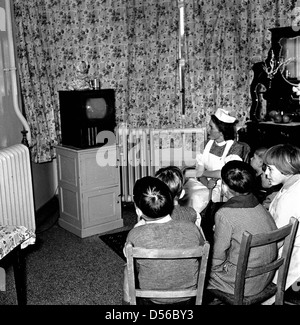 Storico degli anni cinquanta. In Inghilterra. Piccolo gruppo di giovani figli siedono insieme in una stanza di un ospedale con un infermiere, guardando un televisore con un piccolo schermo. Foto Stock