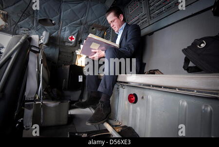 Verteidigungsminister Karl-Theodor zu Guttenberg (CSU) liest am Montag (29.03.10) auf dem Weg von Berlin nach Pristina im Kosovo in einem Transportflugzeug der Bundeswehr. Im Rahmen eines Besuchs zweitaegigen im Kosovo und in Bosnien-Herzegowina trifft zu Guttenberg die dort stationierten Soldaten der Missionen EUFOR und KFOR. Foto: Michael Kappeler/DDP Foto Stock