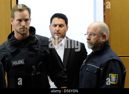 Poliziotti armati portano convenuta Erdal E. (C) nell'aula del tribunale regionale di Darmstadt, Germania, 31 marzo 2010. Insieme con altri due uomini E. è stato accusato di aver ucciso tre persone - tra le quali una donna noninvolved - in uno scontro a fuoco in una gelateria in Ruesselsheim in agosto 2008. I tre sono stati consegnati frasi che vanno tra lif Foto Stock
