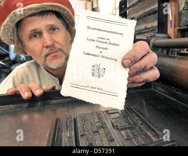 Stampante Andreas Metschke tira su cui la carta stampata di accordo di cooperazione tra Cranach-Cities Kronach e Luther-City Wittenberg fuori da una pressa nella sua officina a Wittenberg (Germania, 13 aprile 2010. I supporti di stampa simbolico per un accordo che è stato firmato dai sindaci delle due città nello stesso giorno. Kronach e Wittenberg desidera collaborare maggiormente in materia di turi Foto Stock