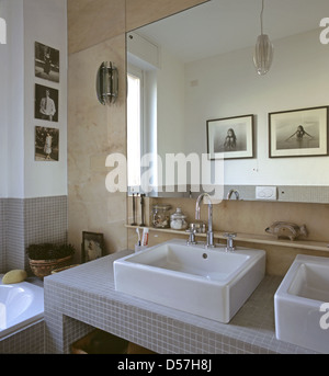 Interno di una stanza da bagno in un appartamento: particolare del lavello e alcune foto incorniciate haned sulla parete Foto Stock
