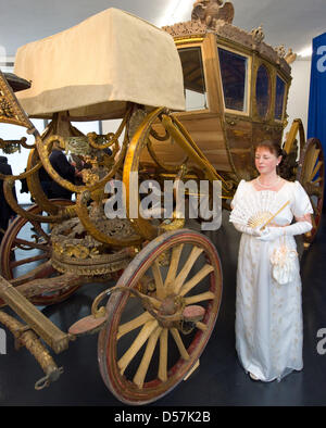 Una donna vestite come Regina Louisa della Prussia pone di fronte alla stato ripristinato il trasporto di re Federico Guglielmo II nel palazzo Paretz vicino a Potsdam, Germania, 20 maggio 2010. Stato ripristinato il trasporto è uno dei momenti salienti del Louisa Anno 2010 e sul display a Paretz palazzo remise dal 22 maggio. Fondazione dei Castelli e dei Giardini Prussiani (SPSG) aveva il carro restaurato che tra Foto Stock